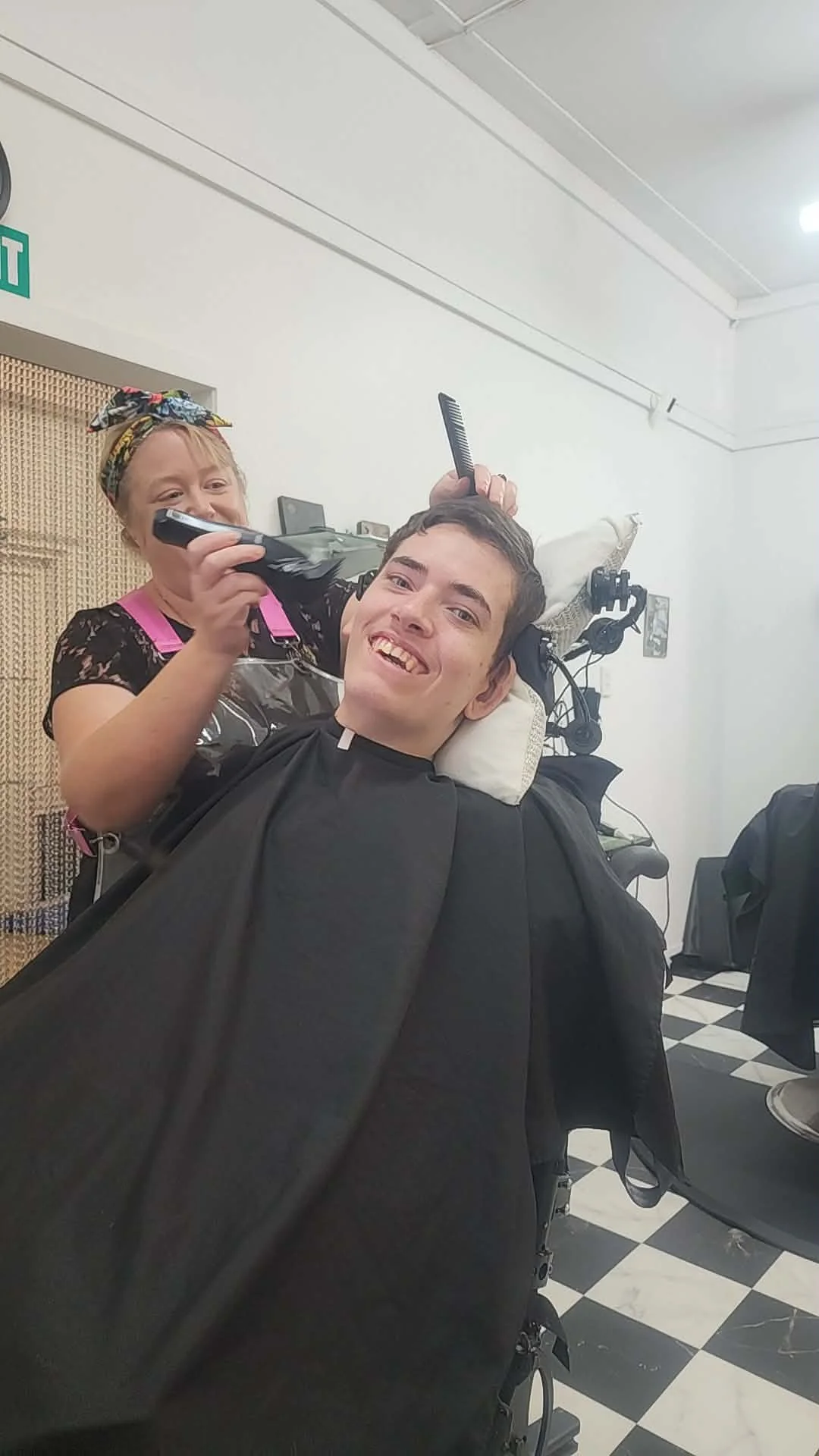 Jodi cutting a client's hair, both laughing
